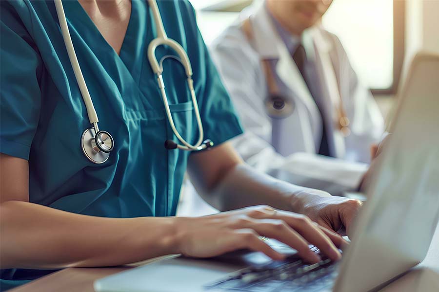 Two doctors in scrubs using a laptop