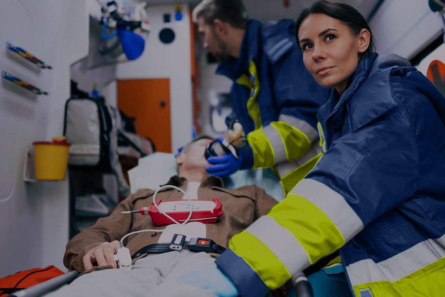 A paramedic team helping a patient in the back of an ambulance