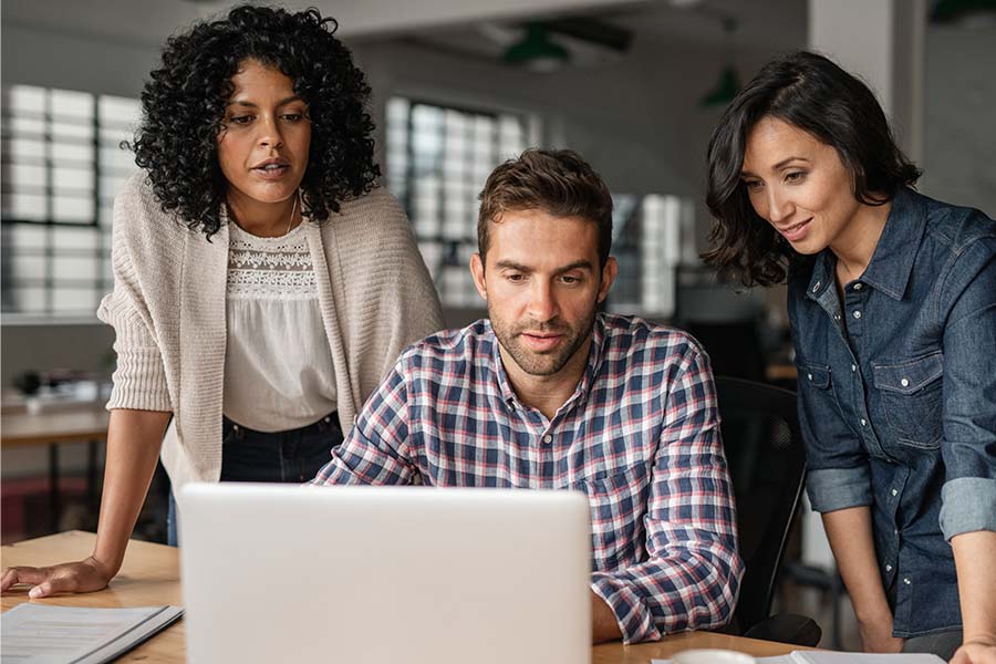 three people looking at a laptop screen