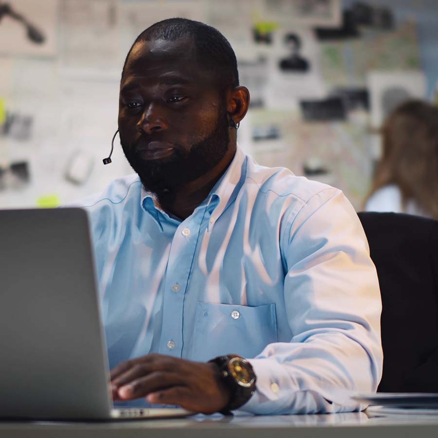 man working on a laptop with an earpiece