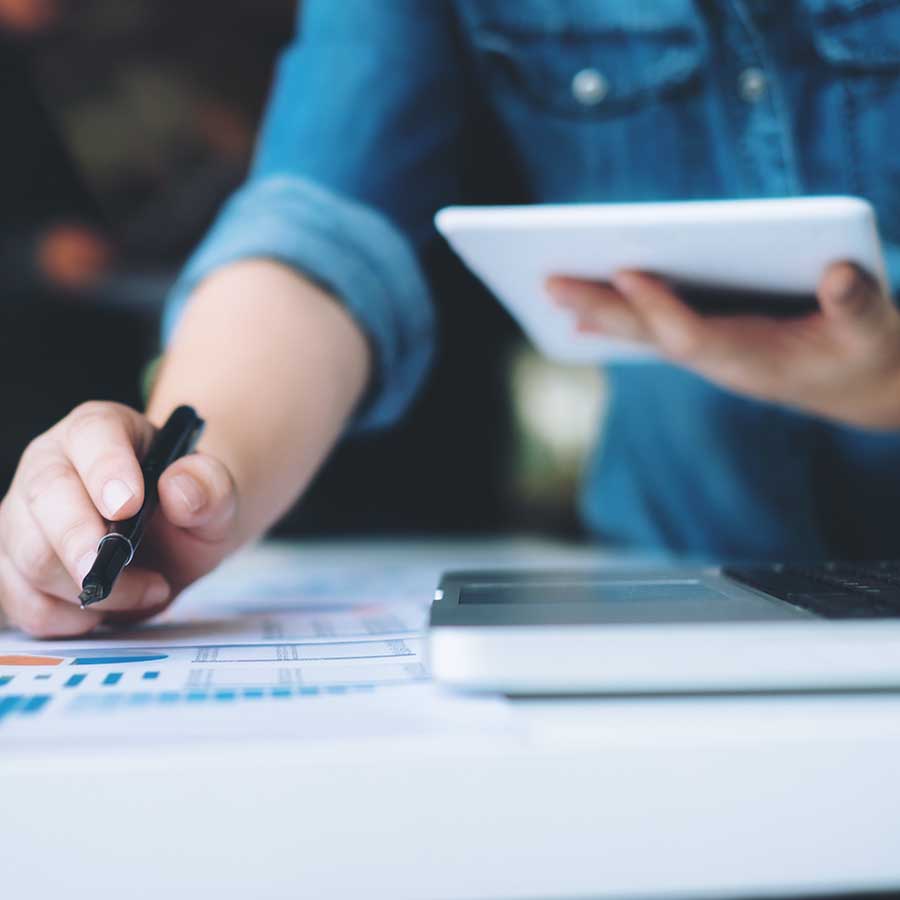 person's right hand holding a pen as left hand holds a tablet