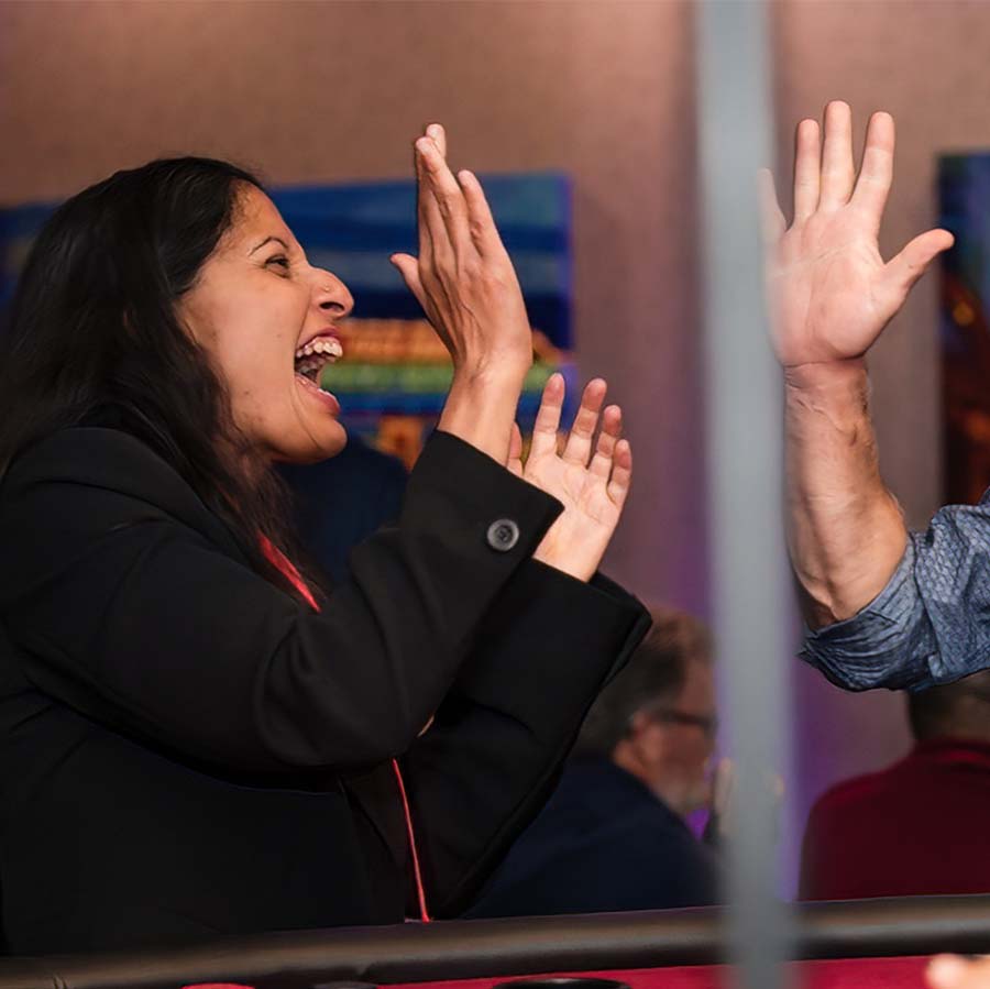 A woman and a man giving each other a high-five with expressions of excitement.